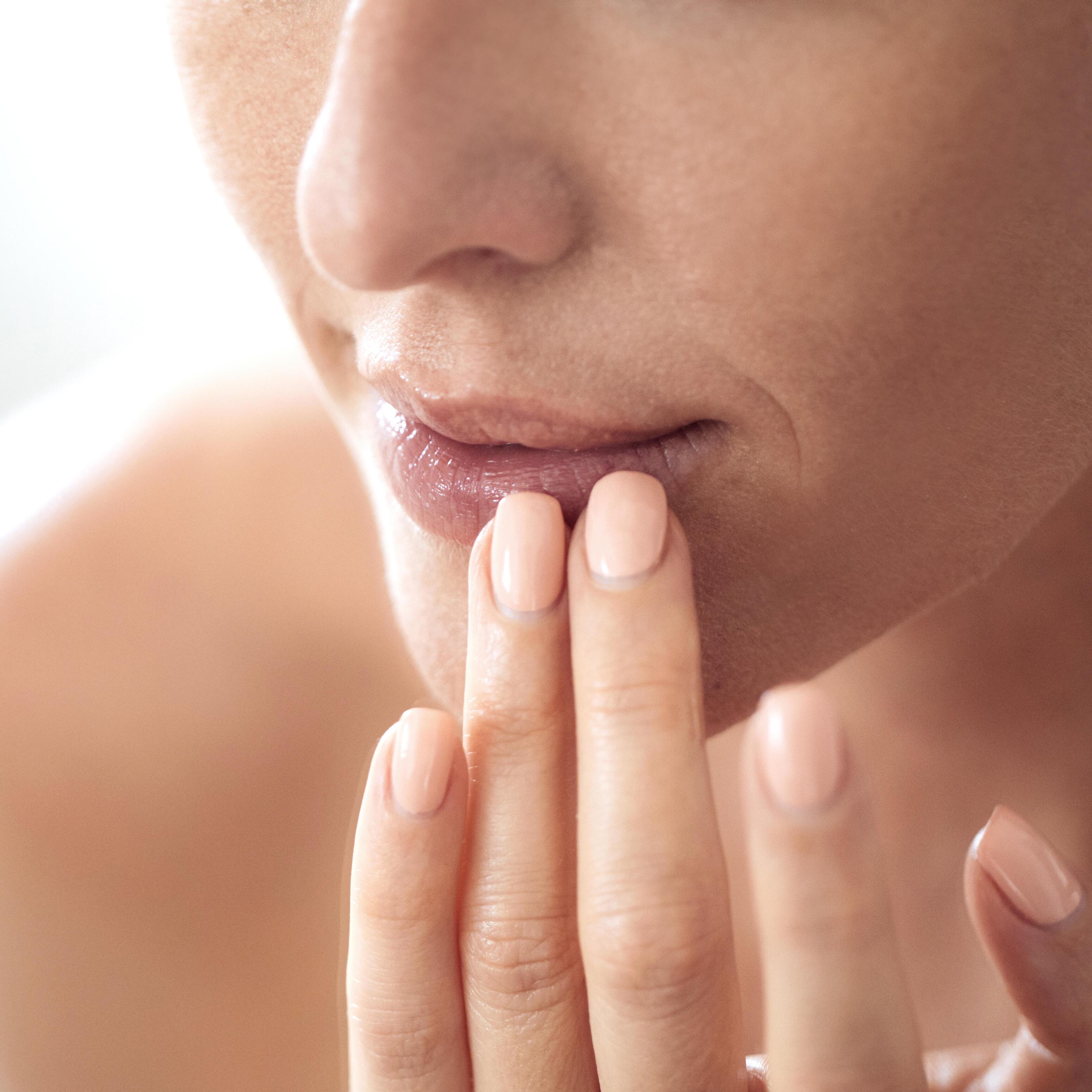 Nærbilde av kvinne som tar seg til munnen og på leppene